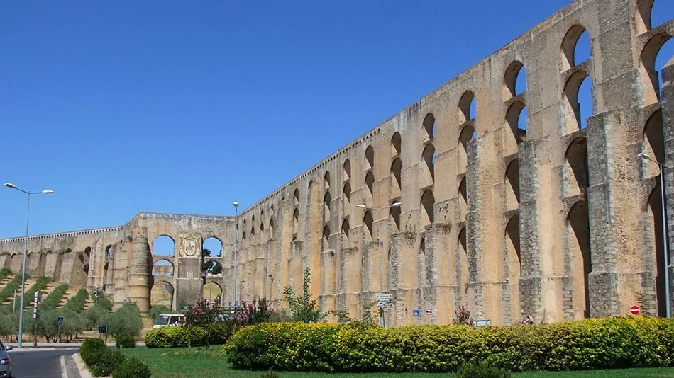 A tall stone aqueduct with rows of arches in the Alentejo