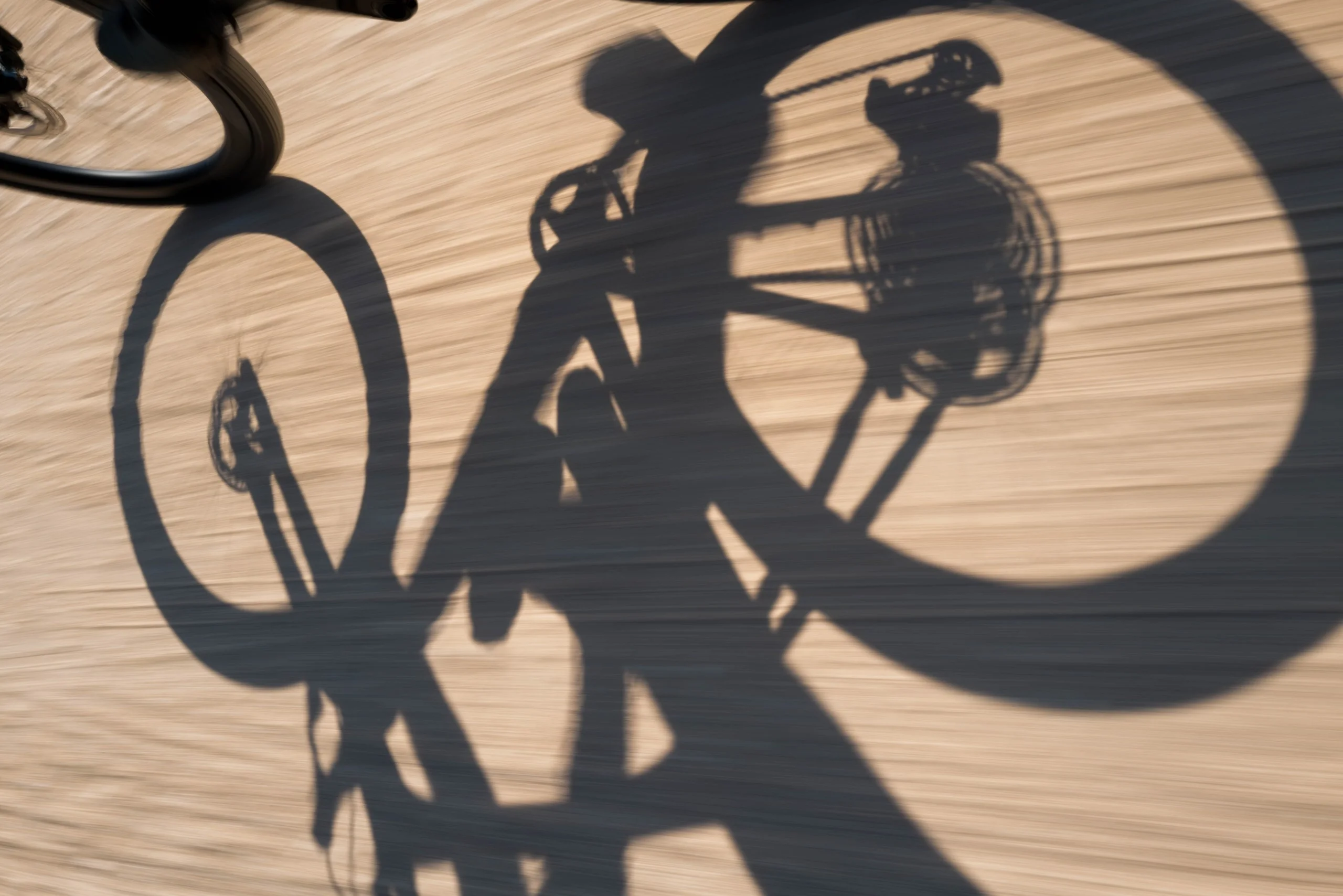 The shadow of a road bike and its rider on a sandy road
