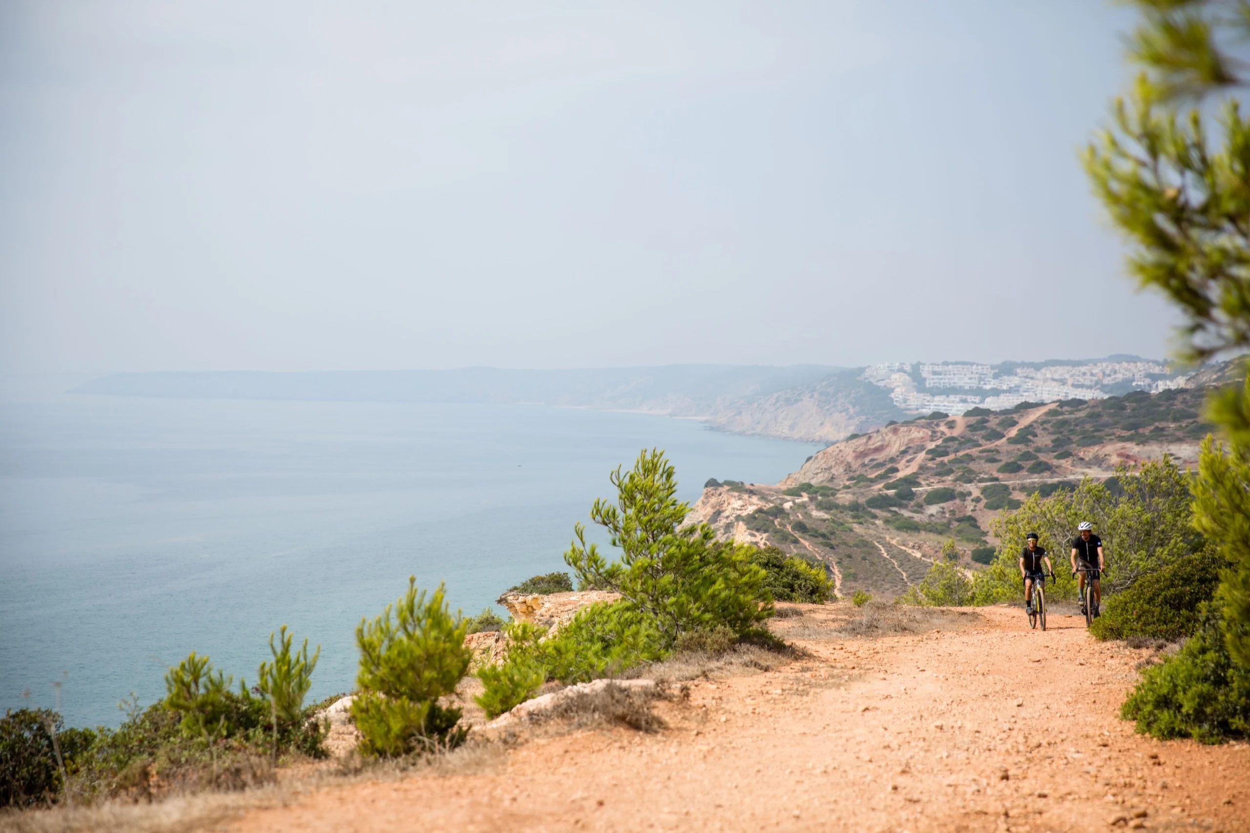 Two cyclists on the coast path west of Lagos in the Algarve, the bay below them