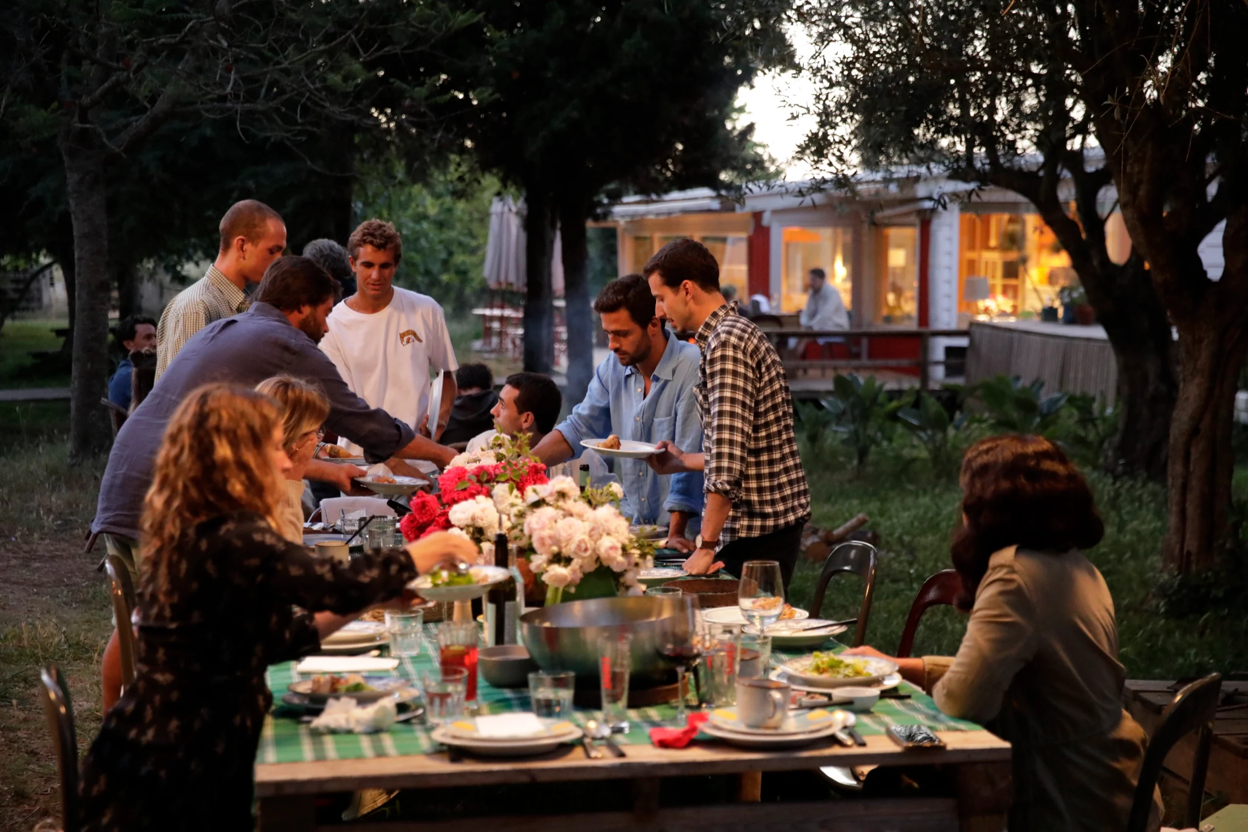 Dinner at a long table in a garden after a day of cycling, plates being shared