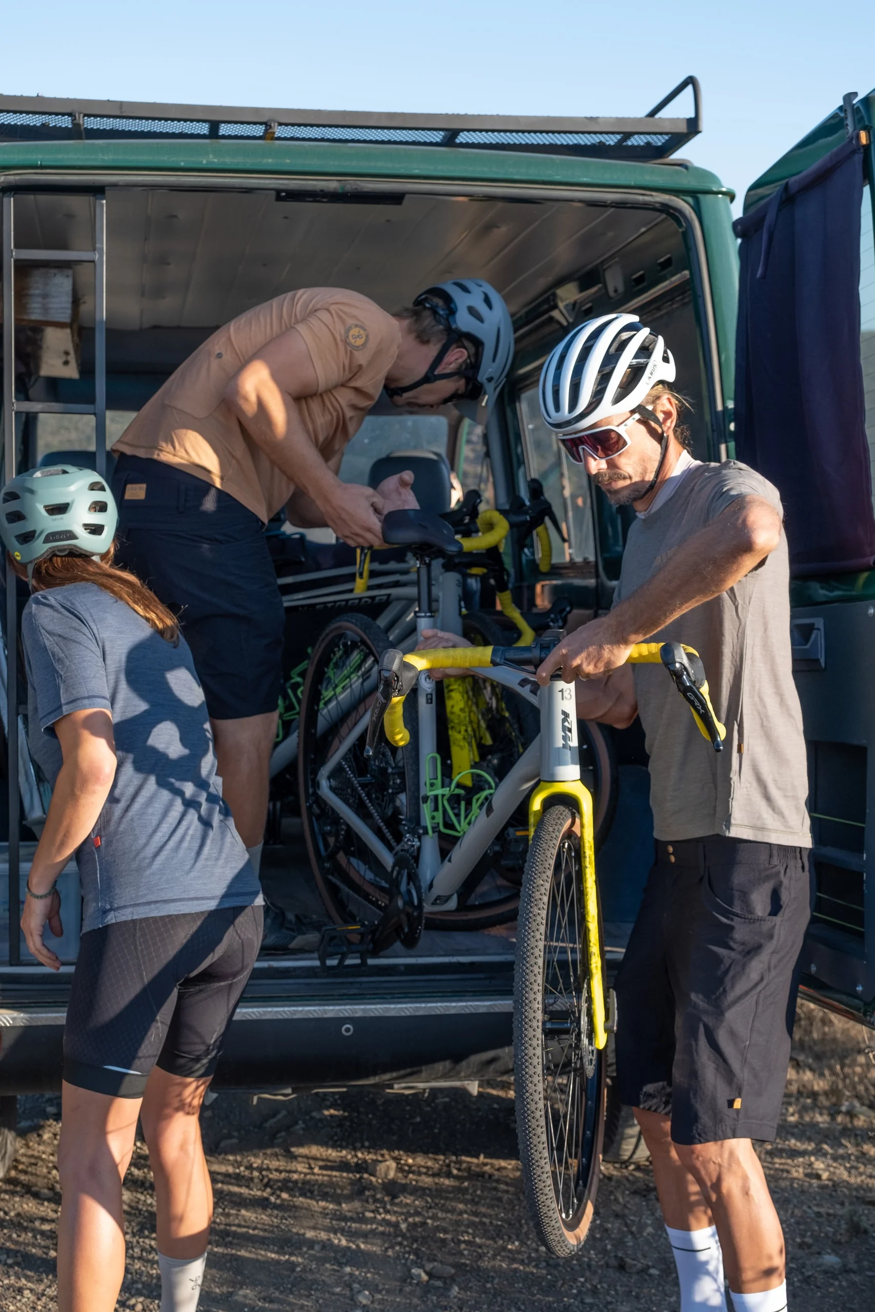 Riders and the mechanic at the support van with a gravel bike