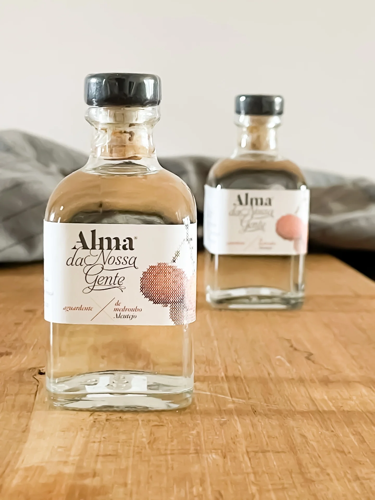 Two small bottles of medronho from a small Alentejo producer on a wooden table