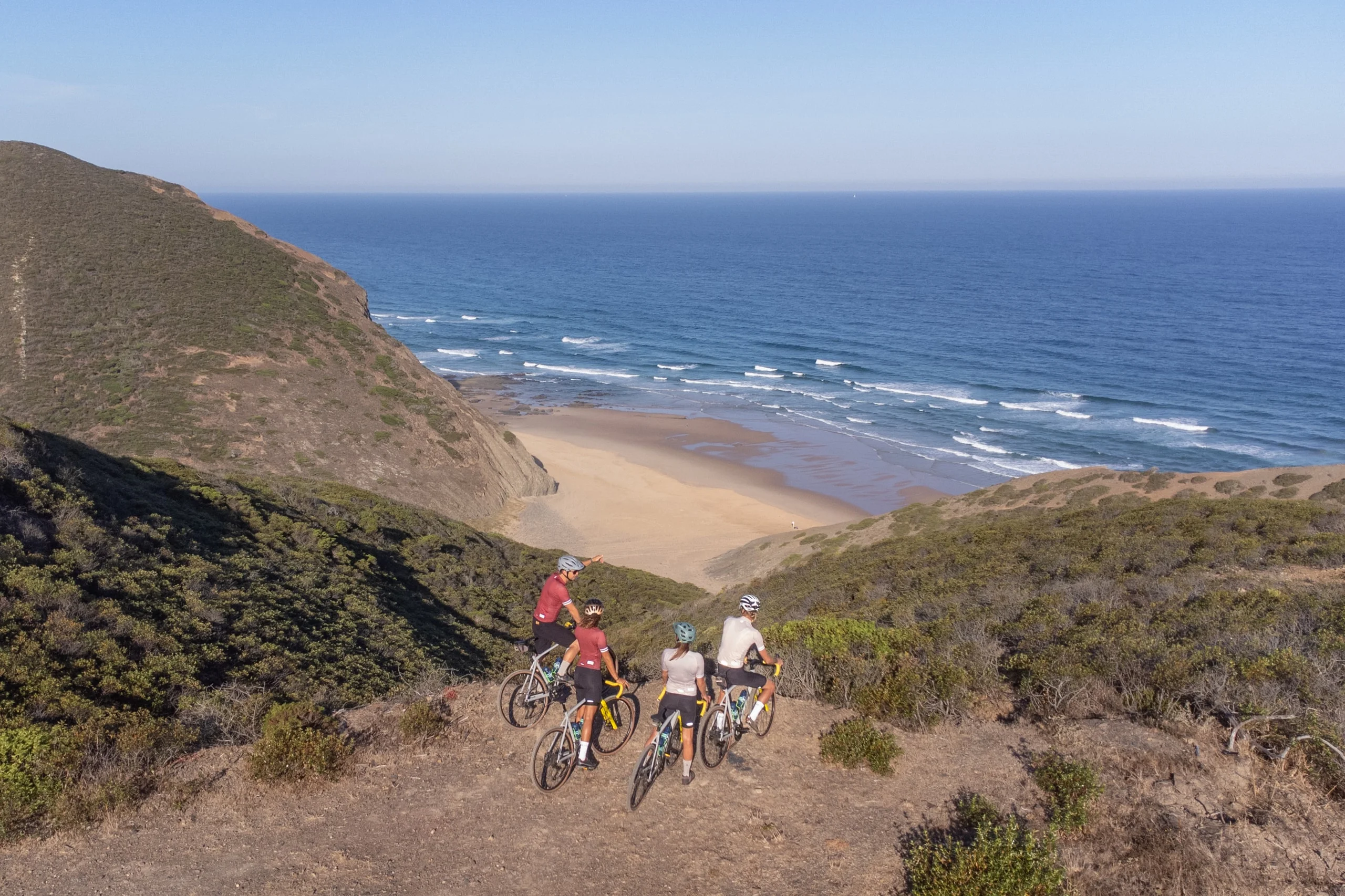 Mountain bikers on the cliff path above a beach on the Costa Vicentina