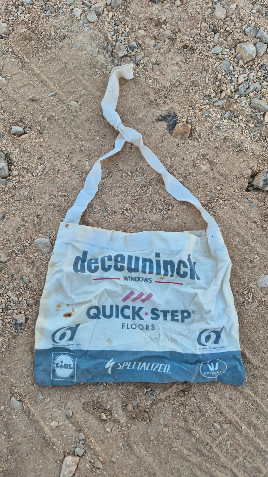 A pro team musette signed by Remco Evenepoel, the cotton feed bag handed up to riders in a race, lying on a gravel track