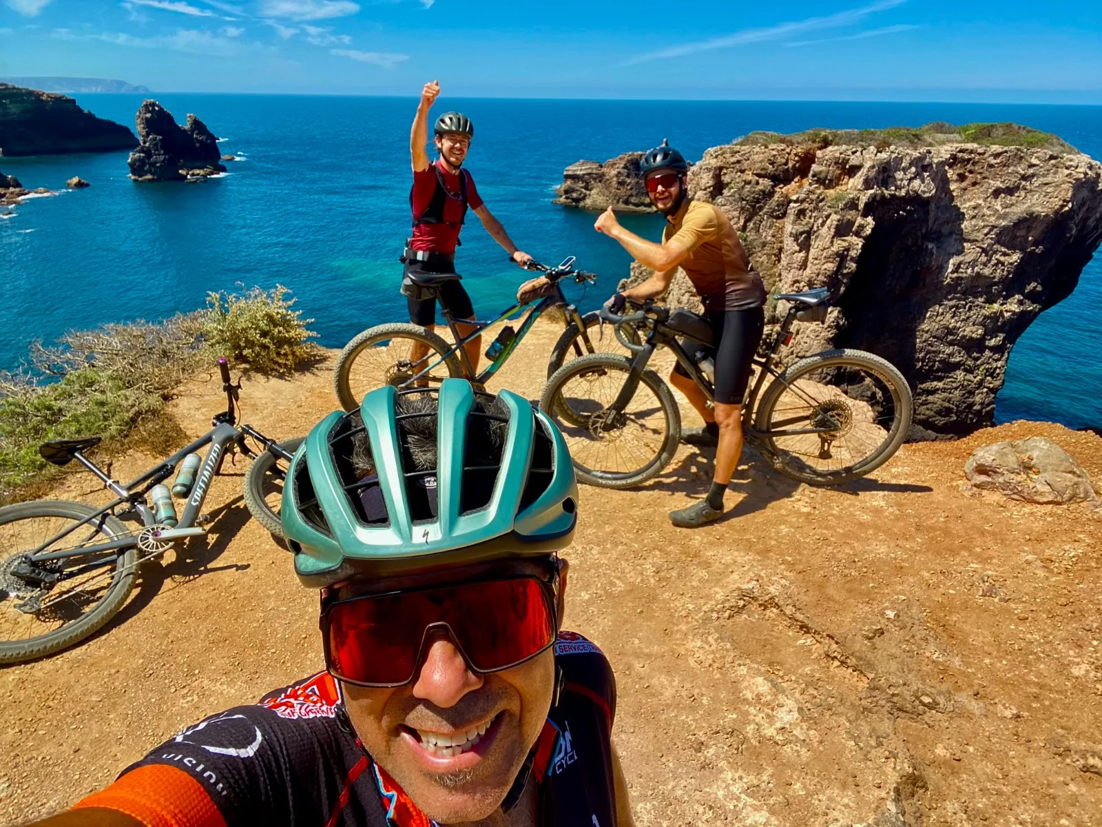 JB, Gregor and Quentin of the Musette team with their mountain bikes on the cliffs near Carrapateira on the Costa Vicentina, the Atlantic behind them