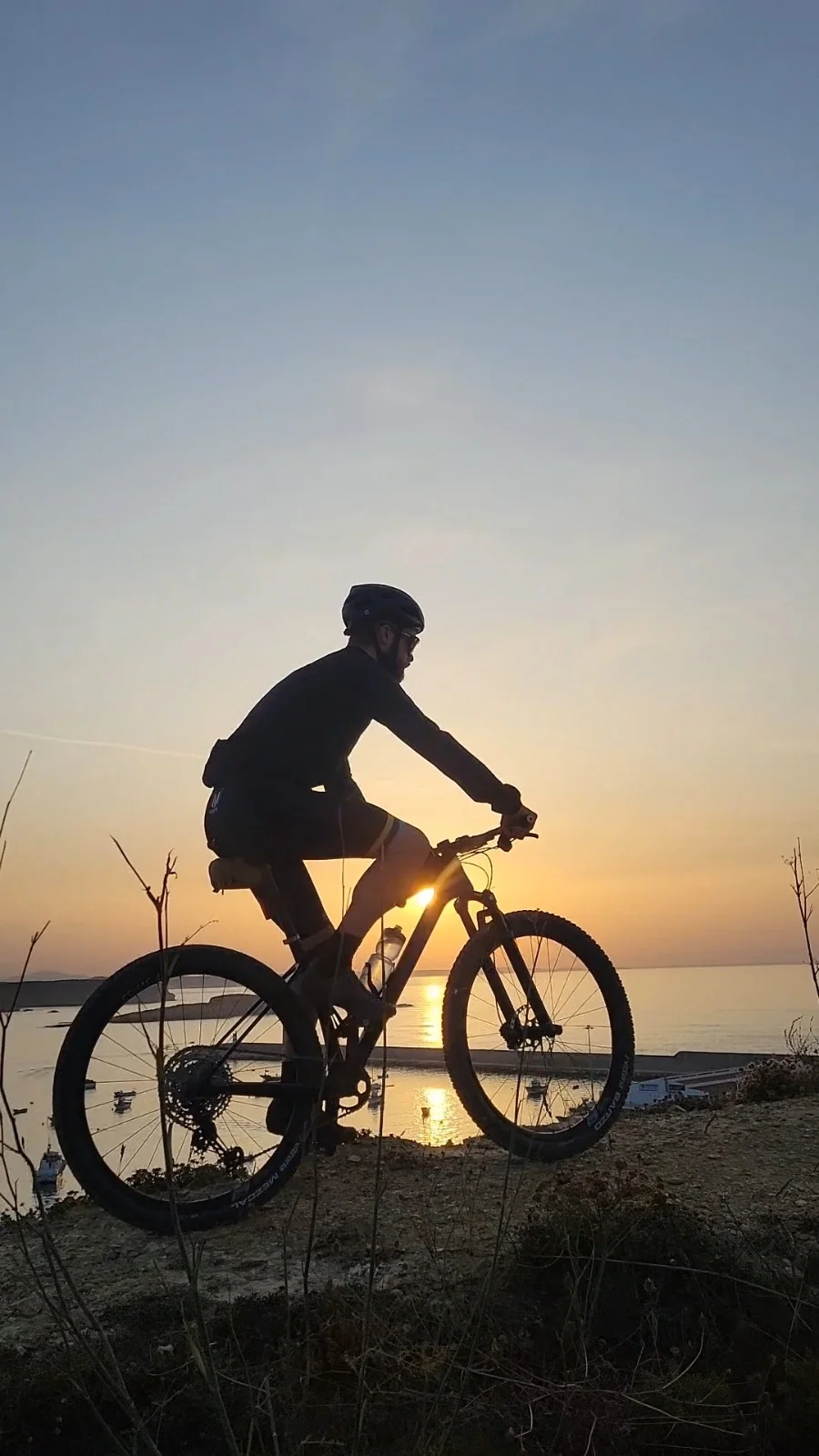 Quentin, cycling guide for Musette Travel, on a mountain bike above the coast at sunset