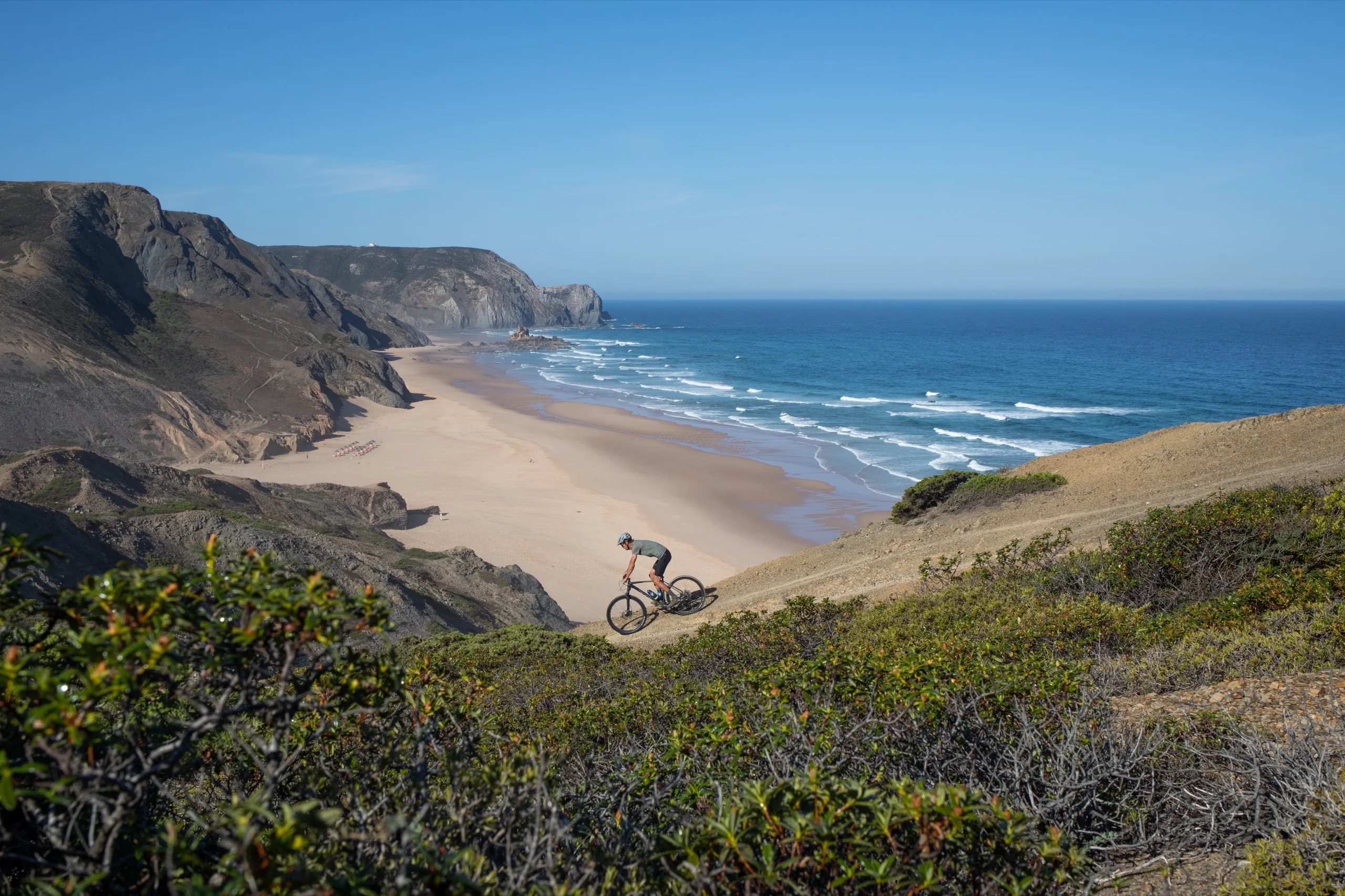 A rider on a cliff track above a long beach on the Costa Vicentina, western Algarve