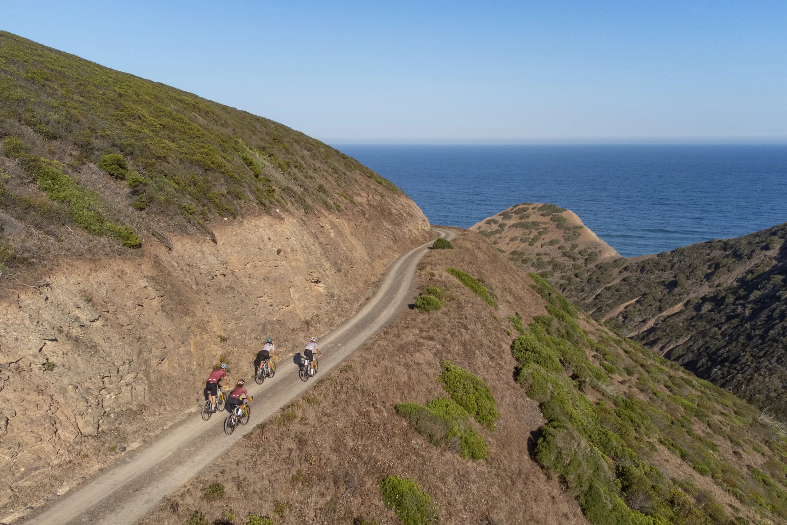 Gravel riders on the cliff track above the Atlantic on the Costa Vicentina, seen from the air