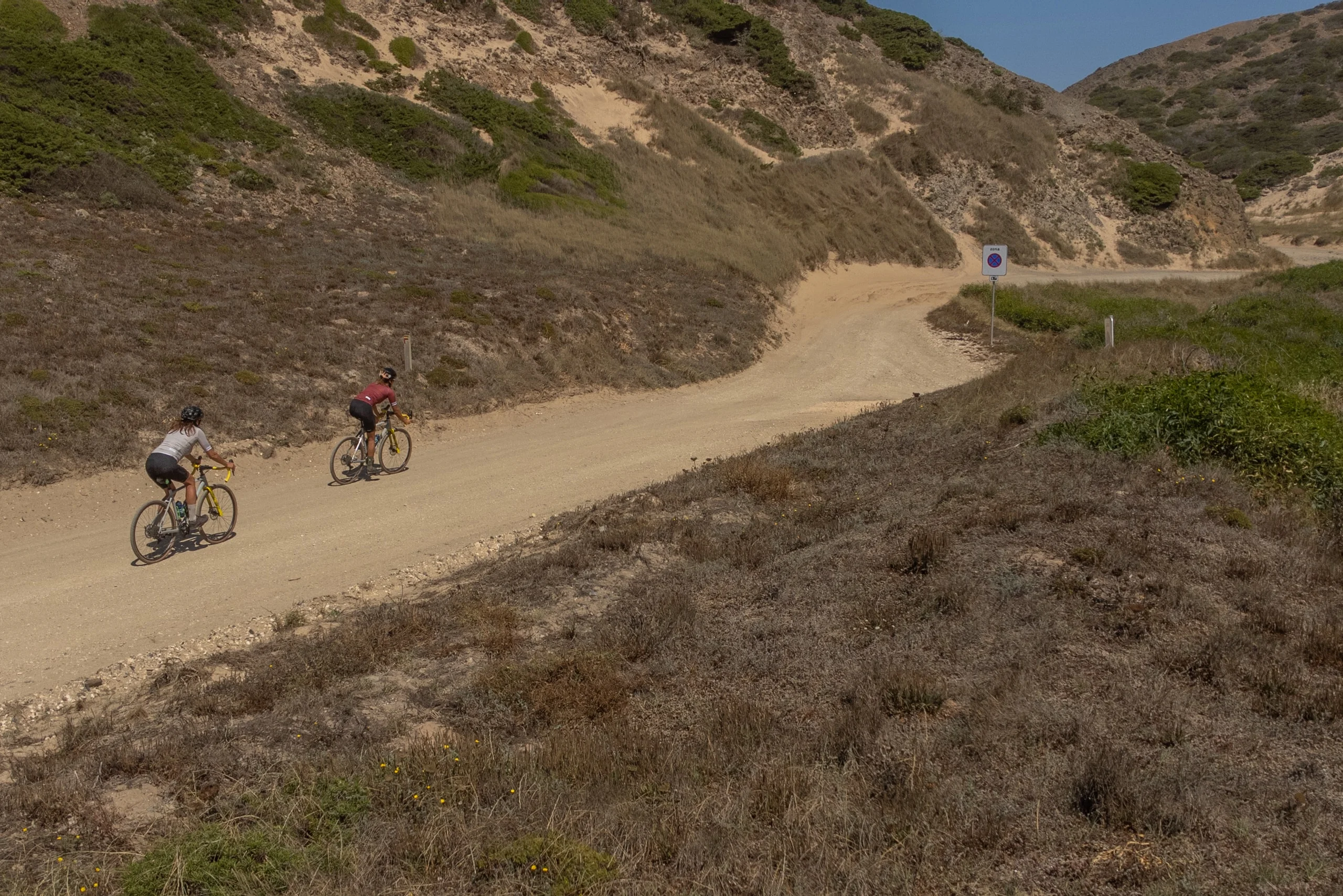 Two gravel riders on an open dirt road through the hills